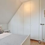 Bedroom with bed, wardrobe, and mirror on the wall.
