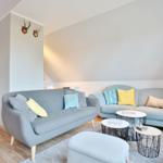 Two gray sofas with cushions, round tables, and floor lamp in living area.
