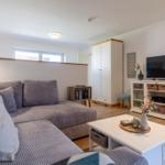 Wohnzimmer mit Sofa, Couchtisch und TV-Schrank. Holzboden und Fenster.