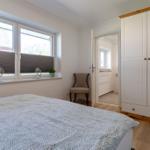 Schlafzimmer mit Bett, Kleiderschrank und Fenster mit Blick auf Dach.