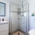 Badezimmer mit Dusche, Waschbecken und Toilette. Fliesen und moderne Einrichtung.