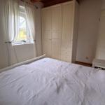 Bedroom with white bed, wardrobe, and window with white curtains.