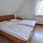 Bedroom with double bed, wooden floor, and window with view outside.