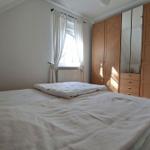 Bedroom with double bed, wardrobe, and window with white curtains.