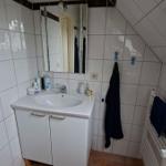 Bathroom with sink, mirror, and heater. Roof slope and shower are visible.