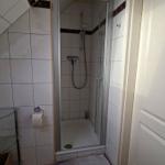 Bathroom with shower, toilet, and glass shelf under sloped ceiling.