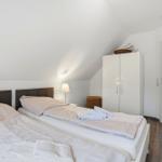 Room with double bed, wardrobe, and nightstand under sloped ceiling