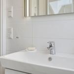 Sink with mirror and chrome faucet in white tiled wall.