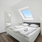 Bedroom with sloped ceiling, double bed, and skylight.