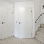 Hallway with two doors and staircase to upper floor.