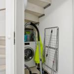 Washing machine and dryer in room with stairs and towel rack.