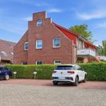 Red brick building with balcony and paved parking area.