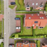House with red roof, paved yard, and green lawn area.