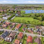 Aerial view of a residential area with houses, green spaces, and a harbor with boats.