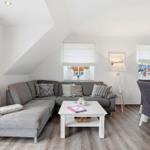 Living room with gray sofa, white coffee table, and dining area.