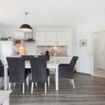 Dining area with table and chairs, kitchen with white cabinets and window
