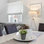 Dining table with chairs and plant. Sofa and floor lamp in background.