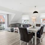 Living and dining area with sofa, dining table, and balcony door.