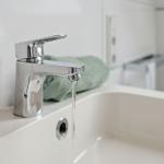 A modern sink with faucet and green towel.