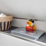A basket with towels and a duck on a sink edge.