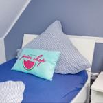 Bedroom with bed, pillows, and nightstand. Blue walls, striped duvet cover.