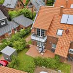 Red roof with solar panels, balcony, and terrace with garden.