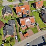 Aerial view of houses with gardens and streets. Some houses have solar panels.