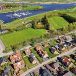 Aerial view of a residential area near a river with marina and sports fields.