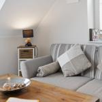A sofa with cushions and a blanket is near a window. A bowl sits on the table.