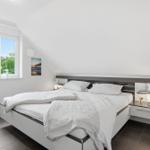 Bedroom with double bed, window, and nightstand.