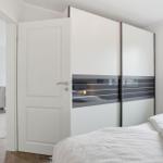 Bedroom with bed, sliding doors, and view into living room.