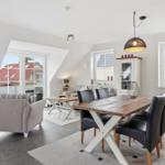 Dining room with wooden table, black chairs, and view to balcony. Living area with sofa and armchair.
