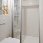Duschkabine mit Duschbrause, Toilette und Meerespferd-Dekoration.