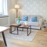 Wohnzimmer mit Sofa, Couchtisch und Tapete mit Krabbenmotiv.