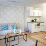 Wohnbereich mit Sofa, Tisch und Küchenzeile. Wand mit Krebsmotivtapete.
