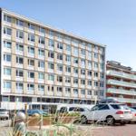 Modern apartment building with balconies and parking space in front.