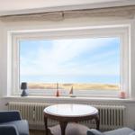 Zimmer mit Blick aufs Meer. Fenster, Tisch, Stühle und Heizkörper sind sichtbar.