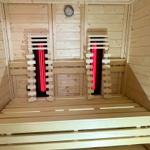 Sauna with wooden bench and red heating elements on the wall.