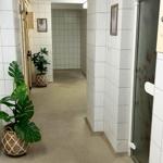 Hallway with white tiles, plants, and doors