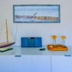 Auf einem Schrank steht ein Segelbootmodell, ein Radio und zwei Rosen in Gläsern.