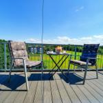Terrasse mit zwei Stühlen und Tisch. Blick auf grünes Feld und Himmel.
