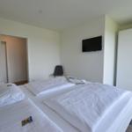 Schlafzimmer mit Doppelbett, Fernseher und Kleiderschrank.