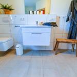 Badezimmer mit Toilette, Waschbecken und Bademanteln.