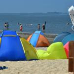Strand mit bunten Strandzelten und Badegästen im Hintergrund. Strandkorb mit Nummer 134.