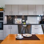 Moderne Küche mit Essbereich, Edelstahlspüle und integriertem Backofen.