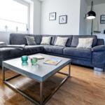 Ein Wohnzimmer mit grauem Sofa, Holzboden und modernem Couchtisch.