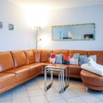 Ein Wohnzimmer mit braunem Ledersofa, Glas-Tisch und Spiegel an der Wand.