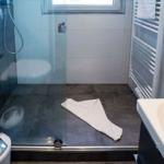 Duschkabine mit Glaswand, Toilette und Handtuch auf dem Boden.