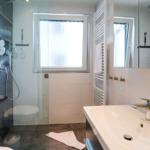 Badezimmer mit Dusche, Waschbecken und Fenster.