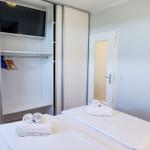Schlafzimmer mit Bett, Kleiderschrank und Fernseher. Handtücher auf dem Bett.